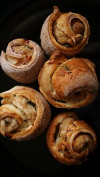 Chicken rolls from puff pastry on a black plate - vertical photo