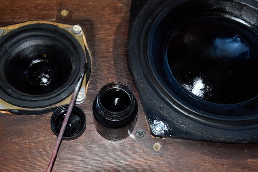 Painting the diffusers of speakers with stamp paint to give them aesthetics. Ink and brush next to the speakers.