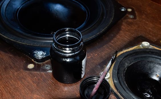 Painting the diffusers of speakers with stamp paint to give them aesthetics. Ink and brush next to the speakers.