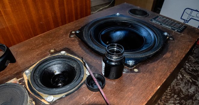 Painting the diffusers of speakers with stamp paint to give them aesthetics. Ink and brush next to the speakers.