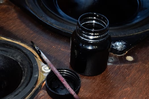 Painting the diffusers of speakers with stamp paint to give them aesthetics. Ink and brush next to the speakers.