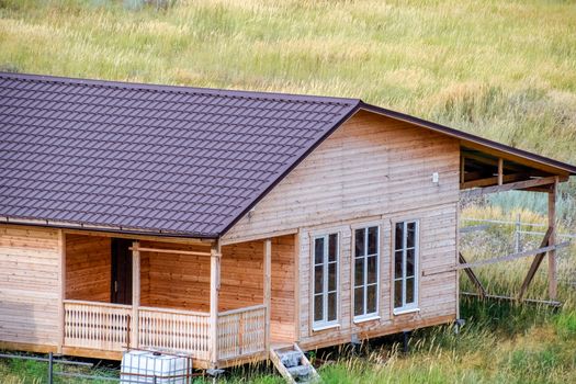 A wooden house made of timber and planks with a roof made of metal. House among the steppe.