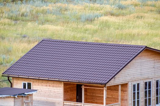 A wooden house made of timber and planks with a roof made of metal. House among the steppe.