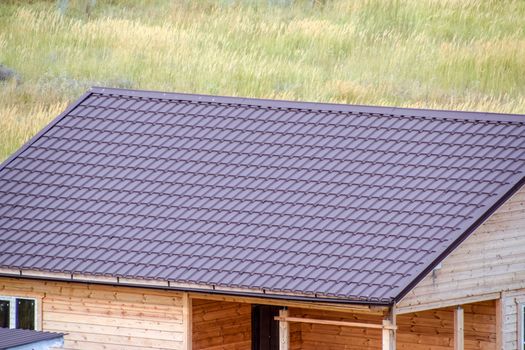 A wooden house made of timber and planks with a roof made of metal. House among the steppe.