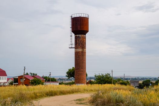 Rusty water tower against the sky. Old water pump.