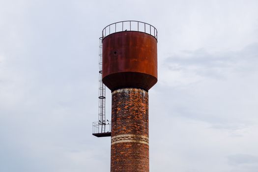 Rusty water tower against the sky. Old water pump.