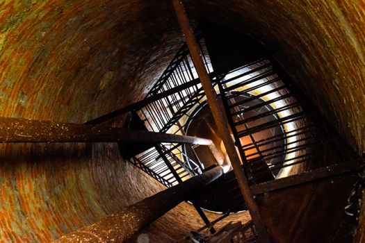 Rusty water tower inside view from top to bottom. Old water pump. Ladder to the water tank, pigeon droppings.