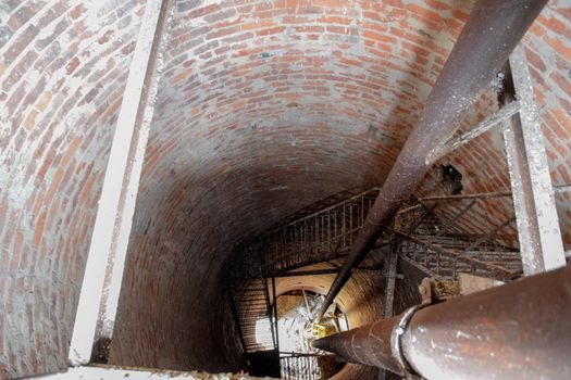 Rusty water tower inside view from top to bottom. Old water pump. Ladder to the water tank, pigeon droppings.