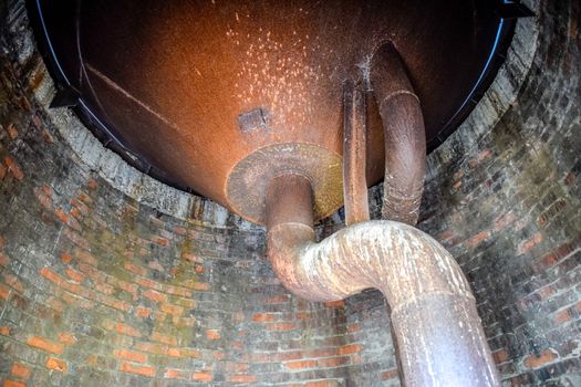 Water tank of an old water tower. Rusty tank and pipes of the water system.