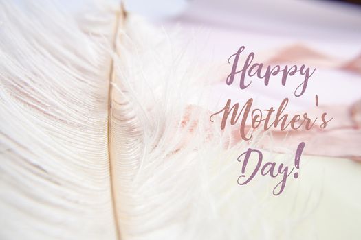 White ostrich feather on pink background. Mother's day greeting card.