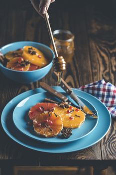 Orange dessert with wine honey or maple syrup and ginger spice, decorated pomegranate berries. Wonderfully sweet, rich and fresh food. Dark rustic background, copy space for you text.