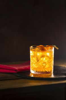 Glass of the cocktail negroni on a old wooden board. Drink with gin, campari martini rosso and orange, an italian cocktail, an aperitif, first mixed in Firenze Italy in 1919 alcoholic bitter cocktail