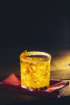 Glass of the cocktail negroni on a old wooden board. Drink with gin, campari martini rosso and orange, an italian cocktail, an aperitif, first mixed in Firenze Italy in 1919 alcoholic bitter cocktail