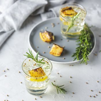 Glasses of Gin and Tonic with Charred Lemon, Rosemary and Coriander is a flavors are perfectly balanced refreshing cocktail. on light background, close up surrounded ingredients.