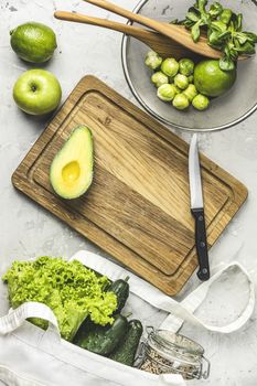 Fresh organic ingredients for salad making on green background. Spring diet, healthy raw vegetarian, vegan concept, detox breakfast, alkaline clean eating. Copy space.