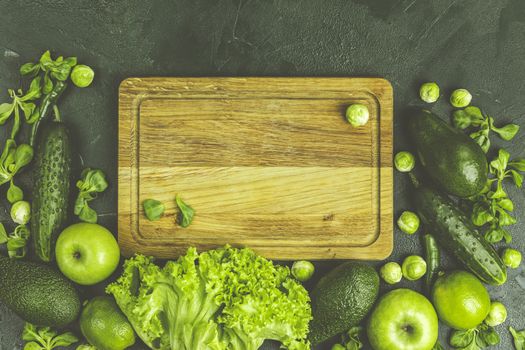 Fresh organic green vegetables and fruits on green background. Spring diet, healthy raw vegetarian, vegan concept, detox breakfast, alkaline clean eating.