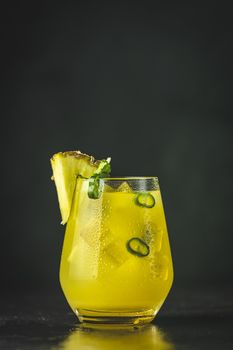 Spicy pineapple jalapeno mezcalita or margarita for Cinco de Mayo is a refreshing cocktail made with pineapple, cilantro, jalapeno and  mexican distilled alcoholic beverage. Black surface