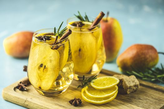 Festive summer drinks, pear spice cocktail. Hot drink cocktail for Christmas, winter or autumn holidays. Served with ingredients on light blue surface.