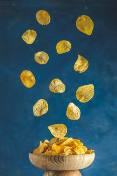 Tasty potato chips falling into blow, frozen in the air. Color of 2020 year. Classic Blue, food trendy art  background.
