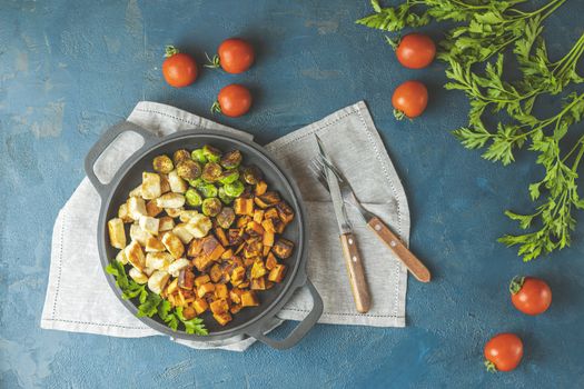 Healthy food. Pan of baking chicken meat, fried sweet potato and brussels sprouts. Top view, classic blue concrete surface, flat lay.