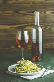 Spaghetti pasta bucatini with pesto sauce and parmesan. Italian traditional perciatelli pasta by genovese pesto sauce in gray dish served with wine	