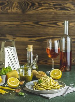 Gray plate of spaghetti pasta bucatini with pesto sauce and parmesan. Italian traditional perciatelli pasta by genovese pesto sauce served with wine