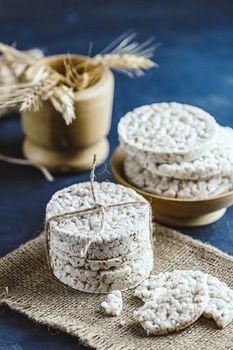 Stack of rice cakes. American puffed rice cakes. Healthy snacks with ears of wheat on classic blue concrete surface. Color of 2020 year. Classic Blue.