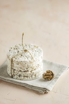 Stack of rice cakes. American puffed rice cakes. Healthy snacks with walnut on light pink concrete surface. Close up.	