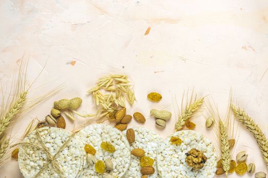 American puffed rice cakes. Healthy snacks with ears of wheat on light pink concrete surface, top view, flat lay, copy space for you text.