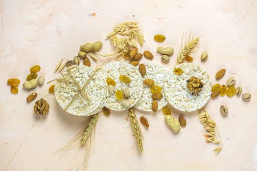 American puffed rice cakes. Healthy snacks with ears of wheat on light pink concrete surface, top view, flat lay, copy space for you text.