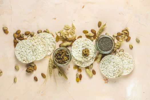American puffed rice cakes. Healthy snacks with ears of wheat on light pink concrete surface, top view, flat lay, copy space for you text.