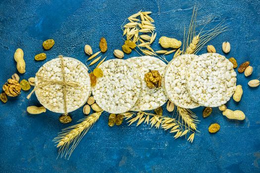 American puffed rice cakes. Healthy snacks with ears of wheat on classic blue concrete surface, top view, flat lay, copy space for you text. Color of 2020 year. Classic Blue, food trendy background.