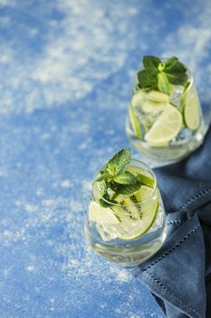 Two detox water or martini tonic cocktail with kiwi, lime, ice and mint. A new kind of mojito with kiwi, lime and mint and of course ice.	