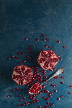 Fresh juicy pomegranate - whole and cut on a dark blue vintage background, top view, horizontal, with copy space