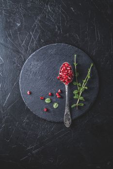 Fresh juicy pomegranate - whole and cut on a black vintage background, top view, horizontal, with copy space