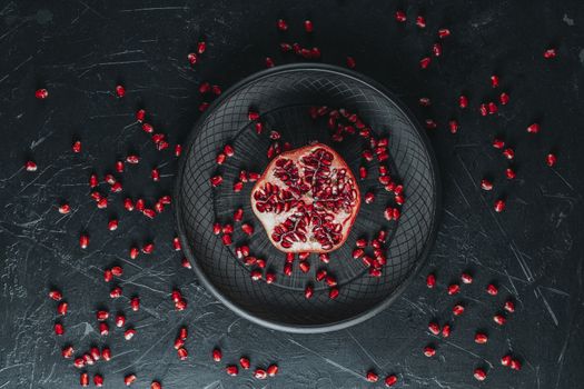 Fresh juicy pomegranate - whole and cut on a black vintage background, top view, horizontal, with copy space