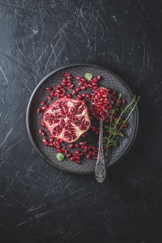 Fresh juicy pomegranate - whole and cut on a black vintage background, top view, horizontal, with copy space