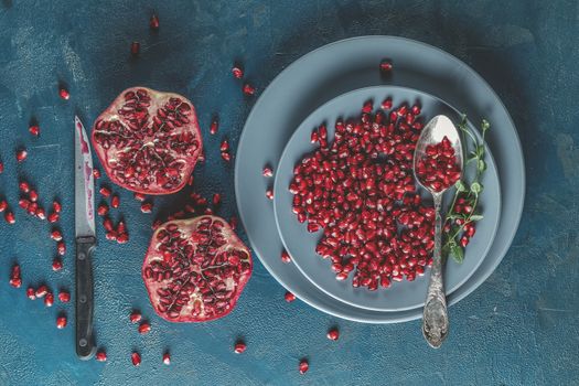 Fresh juicy pomegranate - whole and cut on a dark blue vintage background, top view, horizontal, with copy space	