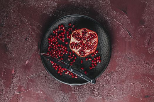 Fresh juicy pomegranate - whole and cut on a dark claret concrete vintage background, top view, horizontal, with copy space	