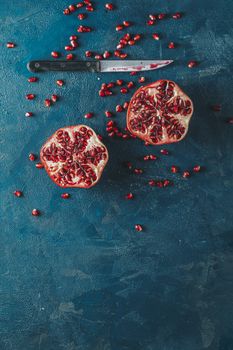 Fresh juicy pomegranate - whole and cut on a dark blue vintage background, top view, horizontal, with copy space	