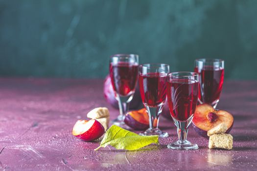 Plums strong alcoholic drink in vintage shots. Hard liquor, slivovica, plum brandy or plum vodka with ripe plums	