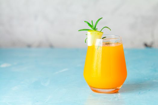 Yellow orange cocktail with melon and mint in glass on blue concrete background, close up. Summer drinks and alcoholic cocktails. Alcoholic or detox cocktail