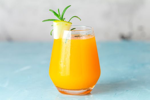 Yellow orange cocktail with melon and mint in glass on blue concrete background, close up. Summer drinks and alcoholic cocktails. Alcoholic or detox cocktail