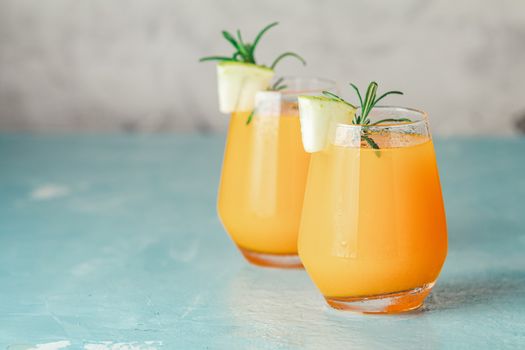 Yellow orange cocktail with melon and mint in glass on blue concrete background, close up. Summer drinks and alcoholic cocktails. Alcoholic or detox cocktail.