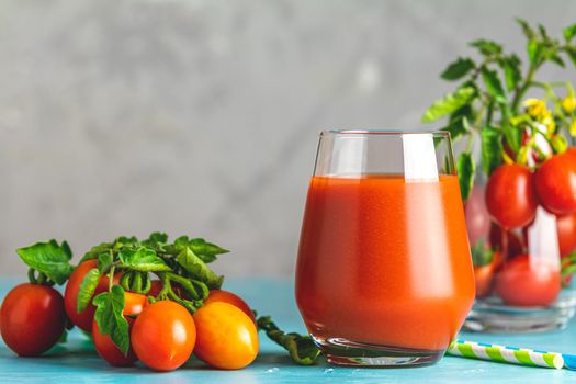 Glass of fresh delicious jummy red tomato juice and fresh tomatoes on light concrete surface. Close up. Gmo free. Natural good food.