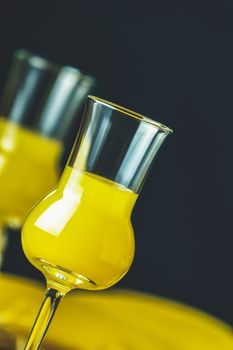 Banana flavoured liqueurs, which French call creme de banana, in  grappas wineglass on dark concrete surface. European aperitif drink. Selective focus, shallow depth of the fields, copy space.