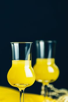 Banana flavoured liqueurs, which French call creme de banana, in  grappas wineglass on dark concrete surface. European aperitif drink. Selective focus, shallow depth of the fields, copy space.