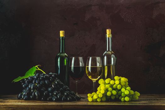 Glasses and bottles of wine and grapes on dark claret bordeaux concrete surface background