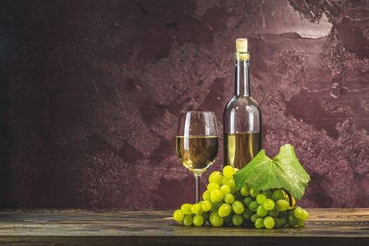 Glasses and bottles of wine and grapes on dark claret bordeaux concrete surface background