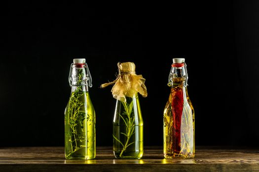 Different sorts of cooking oil, Assortment of sunflower, corn, olives oils with herbs and spices in different bottles on dark background